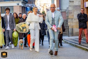 After the civil ceremony at Montauban town hall in Tarn-et-Garonne, the groom is captured playfully riding a toy unicorn, adding a whimsical and lighthearted touch to the celebration just outside the municipal building.
